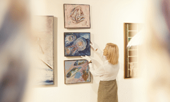 Lady adjusting paintings with gloves on