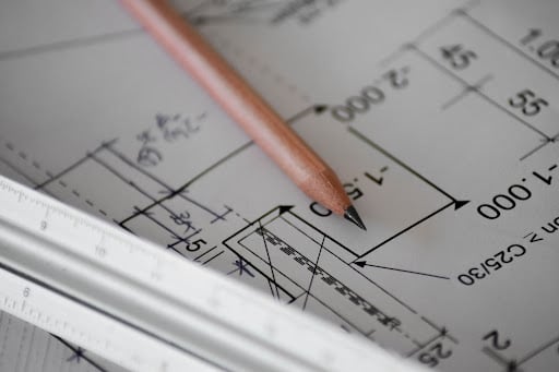 Brown pencil on top of a detailed floor plan with measurements