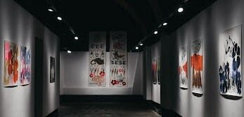 Colourful art hung in a dark hallway in an art gallery as part of an exhibition-Cropped